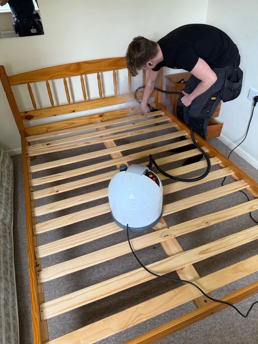 Technician applying steam to the joints of a wooden bed frame